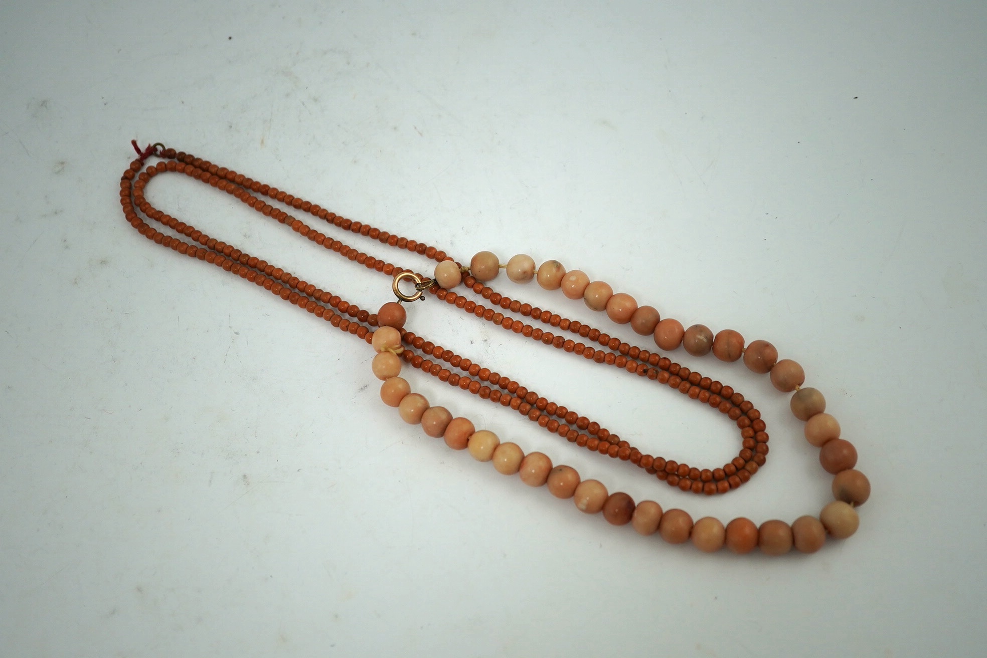 A Chinese coral bead rosary, 58cm drop and a pink soapstone bead necklace, 19.5cm. Condition - fair